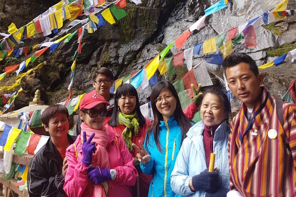 Tourist and guide in front of prayer flag laya trek